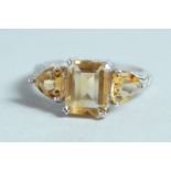 A SILVER AND CITRINE THREE STONE RING.