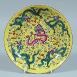 A CHINESE FAMILLE JAUNE CIRCULAR DISH decorated with dragons. 8ins diameter.
