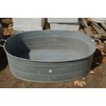 A large oval galvanised bath tub