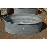 A large oval galvanised bath tub.