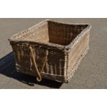 A large wicker laundry basket with cast iron castors.