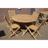 A circular hardwood folding garden table with four chairs.