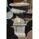 A composite urn shaped planter on pedestal base.
