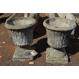 A pair of small composite urn shaped planters.