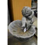 A cast lead cherub and shell bird bath.