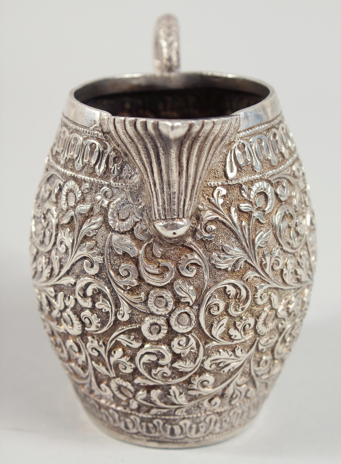 AN INDIAN WHITE METAL ENGRAVED AND CHASED CREAM JUG, with scrolling foliate decoration. 9.5cm high. - Image 2 of 6