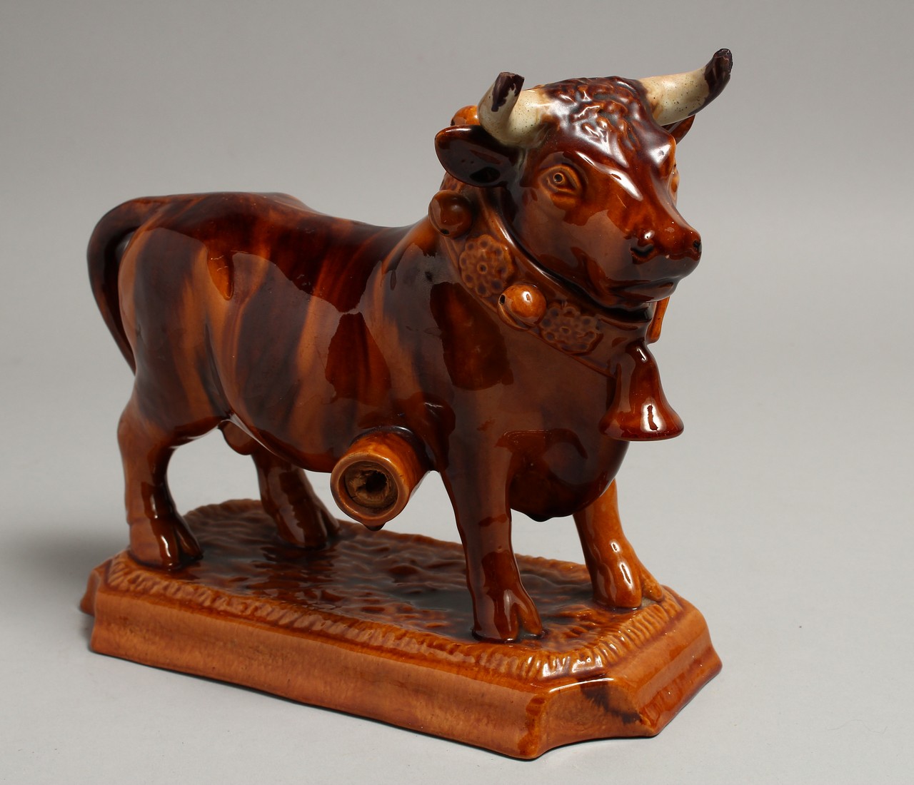 A PORTUGUESE POTTERY BULL on a rectangular base. 10ins long.