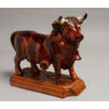 A PORTUGUESE POTTERY BULL on a rectangular base. 10ins long.