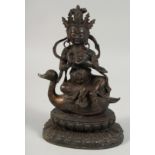 A LARGE BRONZE FIGURE OF A SEATED DEITY, sat upon a bird and on a lotus base, with traces of gilt,