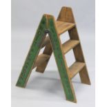 A NOVELTY PAIR OF GREEN FOLDING WOODEN STEPS.