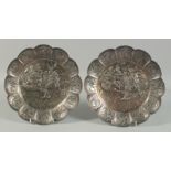 A PAIR OF JAPANESE SILVERED SHAPED DISHES repousse with warriors.