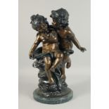 AFTER A. MOREAU A TWO COLOUR BRONZE OF TWO CHERUBS on a circular marble base. 1ft 9ins high.