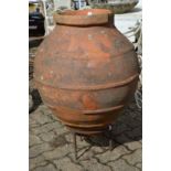 A large Continental terracotta jar on wrought iron stand.