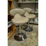 A pair of modern upholstered and chrome bar stools.