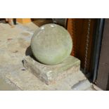 A large composite weathered garden orb on square base.