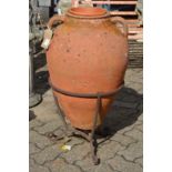 A large continental terracotta twin handled urn with wrought iron stand.