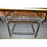 A wrought iron and glass two tier coffee table.