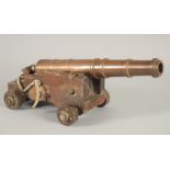 A GOOD SMALL BRONZE CANNON on a wooden carriage with four wooden wheels.