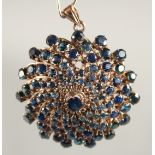 A 14CT GOLD SAPPHIRE SWIRL BROOCH-PENDANT.