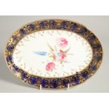 A GOOD OVAL DISH with blue and gilt border and painted with flowers. 11ins wide.