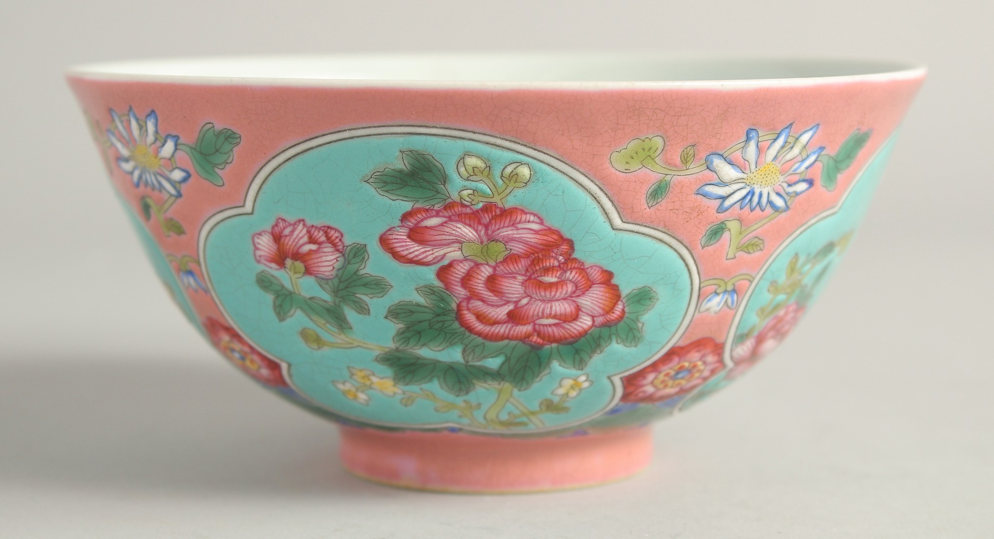 A CHINESE FAMILLE ROSE PORCELAIN BOWL, decorated with turquoise panels of native flora. 15ins