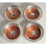 A SET OF FOUR SILVER PLATED CIRCULAR WINE COASTERS with turned down bases.