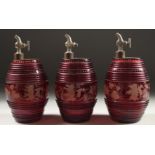 A SET OF THREE BOHEMIAN RUBY GLASS BARRELS engraved with deer and dogs, with chrome tops.