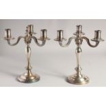 A PAIR OF CHRISTOFLE SILVER PLATED THREE BRANCH CANDELABRAS ON circular loaded bases. 10ins high.
