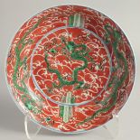 A CHINESE IRON RED GROUND PORCELAIN DISH painted with green dragons on stylised waves. 24.5cm