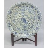 A VERY LARGE CHINESE MING STYLE BLUE AND WHITE PLATTER on a wooden stand. 3ft diameter.