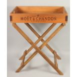 A WOODEN MOET & CHANDON BUTLER'S TRAY AND STAND. 2ft 2ins long.