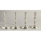 A SET OF FOUR SILVER GEORGIAN STYLE CANDLESTICKS with circular loaded bases. 6.5ins high.