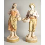 A LARGE PAIR OF ROYAL DUX FIGURES OF A GARDENER AND WIFE both carrying baskets, on circular bases.