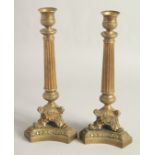 A PAIR OF EMPIRE ORNATE CANDLESTICKS on shaped triangular bases. 11.5ins high.