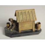 A BRONZE INKWELL, DOG IN A KENNEL on a marble base. 5ins long.