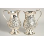 A GOOD PAIR OF CONTINENTAL SILVER PLATED WATER JUGS with floral repousse decoration. 9.5ins high.