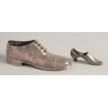 A LARGE SILVER SHOE, 4.75ins long, Birmingham 1903, and another, 2.5ins long. Birmingham 1938 (2).