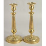 A PAIR OF EMPIRE ORNATE CANDLESTICKS on circular bases. 11ins high.