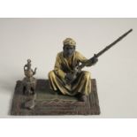 A COLD CAST MODEL OF A MAN holding a gun and sitting on a carpet. 5ins high.
