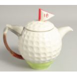 A TONY WOOD GOLF BALL TEA POT AND COVER. 8ins high.