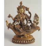 A CHINESE GILT BRONZE GOD seated on a dragon. 10ins high.