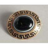 A VICTORIAN GOLD AND BLUE ENAMEL CIRCULAR BROOCH with key pattern decoration and with a single agate