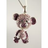 A SILVER TEDDY BEAR PENDANT set with pink stones.