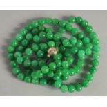 A GOOD STRING OF JADE PEARLS with gold and diamond clasp. 46ins long.