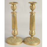 A PAIR OF EMPIRE ORNATE CANDLESTICKS on circular bases. 11ins high.