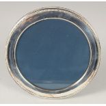 A ROUND SILVER PHOTOGRAPH FRAME with bead edge. 6ins diameter.