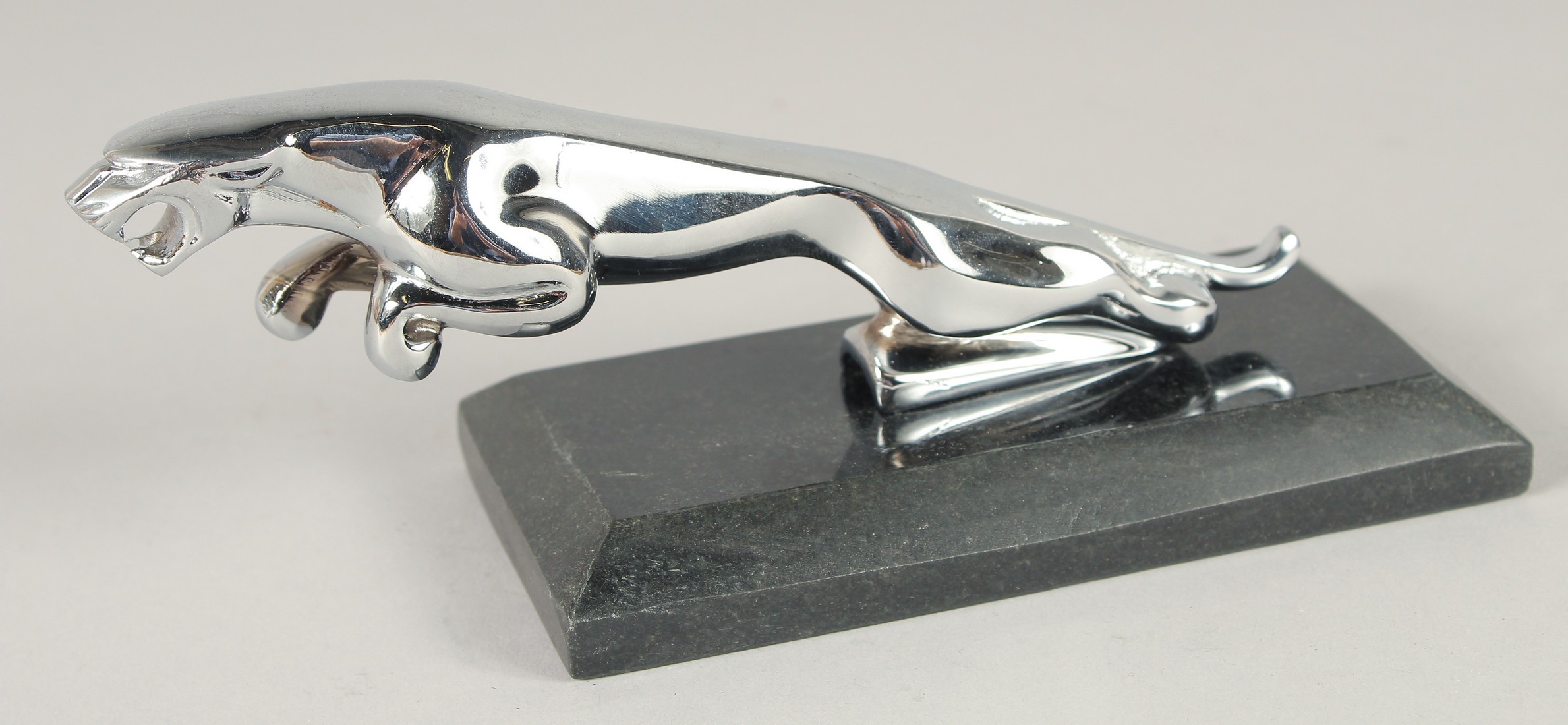 A CHROME JAGUAR CAR MASCOT on a marble base. 7ins long.