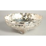 A CONTINENTAL SILVER PLATED CIRCULAR HAMMERED BOWL supported on three shell feet. 9.5ins diameter.