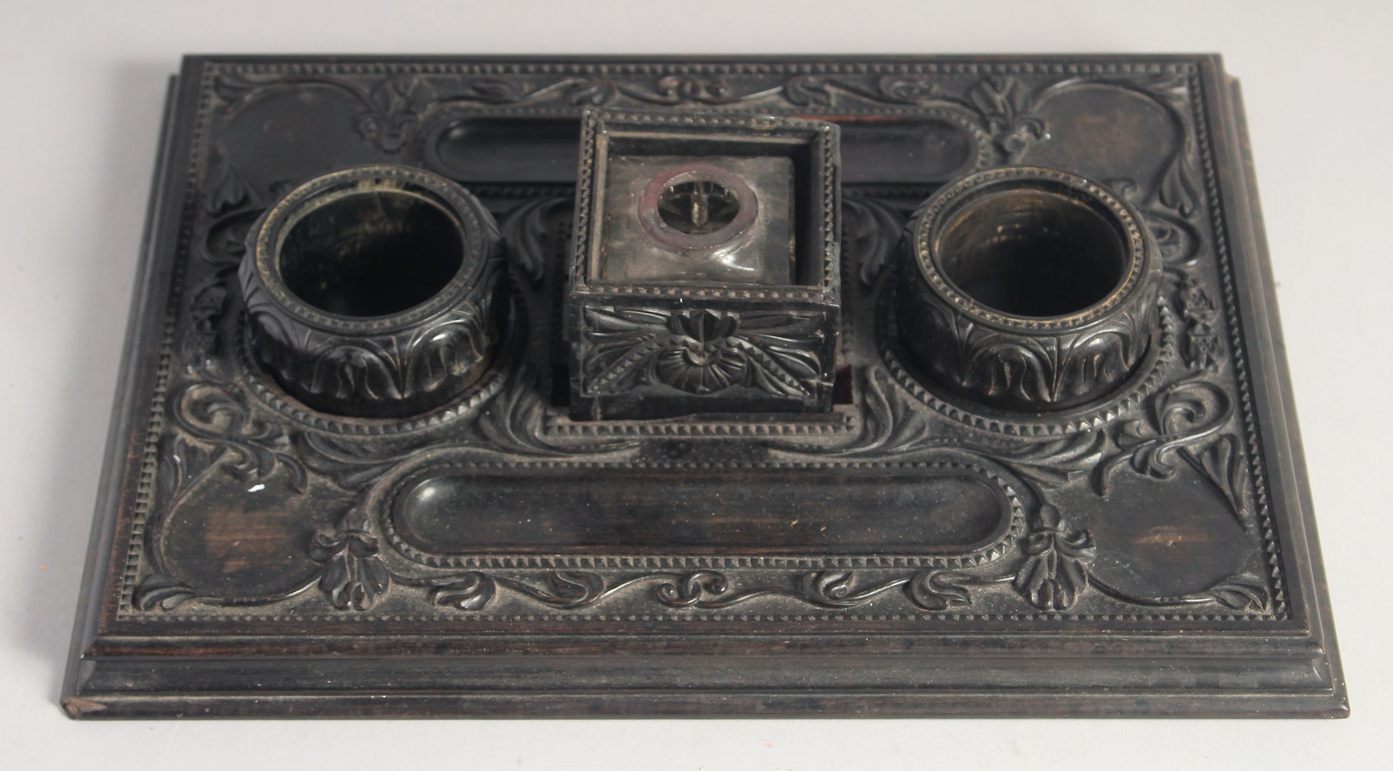 A FINELY CAREVD EARLY 19TH CENTURY SRI LANKAN CEYLANESE EBONY INK DESK STAND, with a central inset