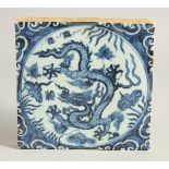 A CHINESE BLUE AND WHITE GLAZED TEMPLE TILE, painted with a dragon and lotus. 19.5cm square